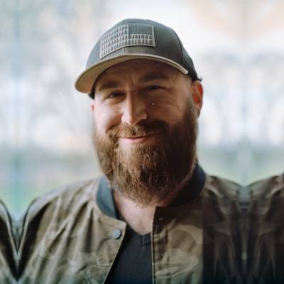 Kenneth Stevenson smiling in a camo bomber jacket and gray cap